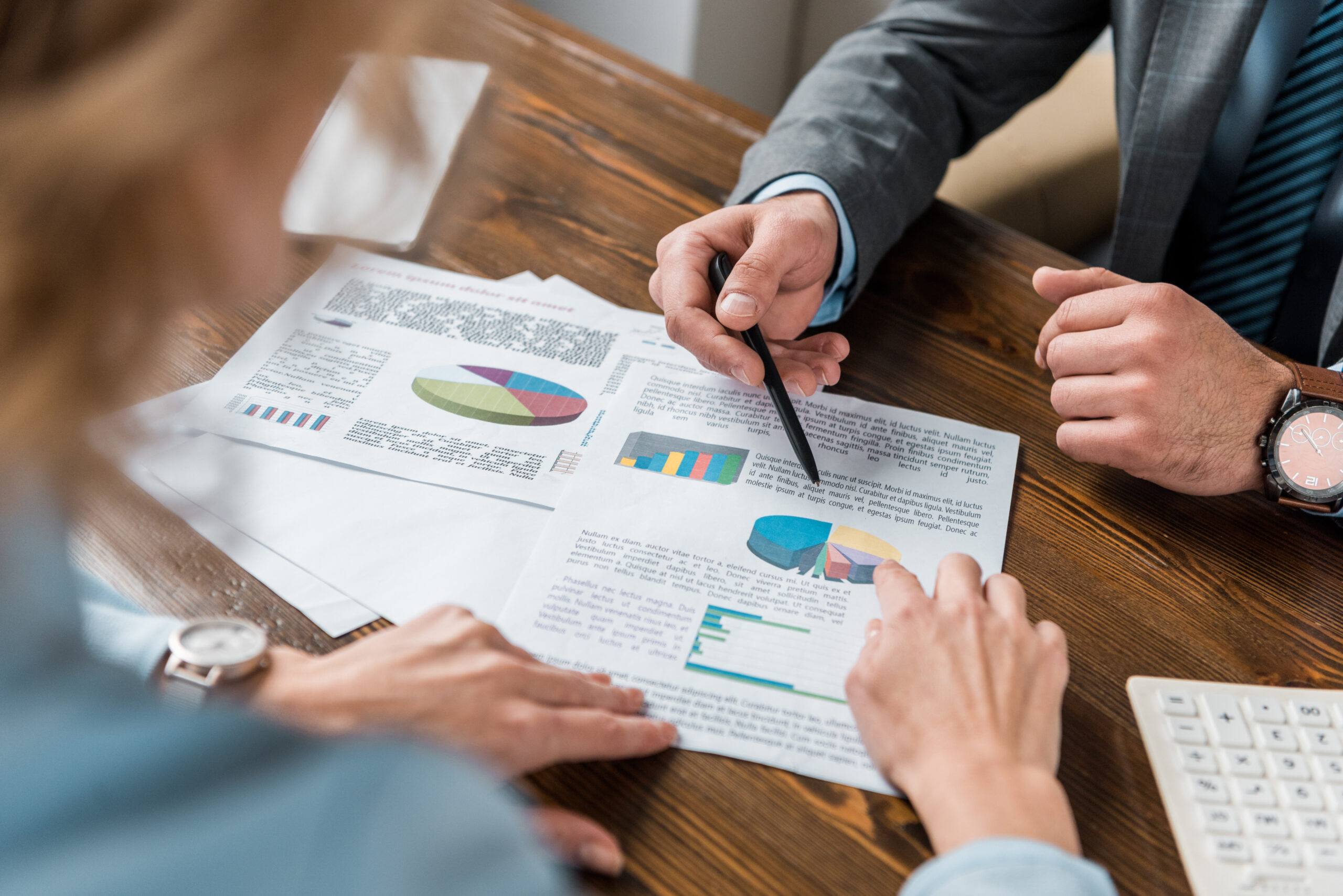 partial view of business people working with charts and graphs in office