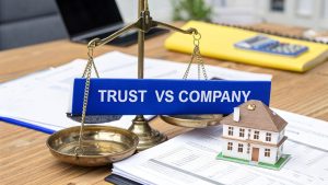 Balance scale comparing “Trust vs Company” with documents and a model house, representing business structure and asset decisions.