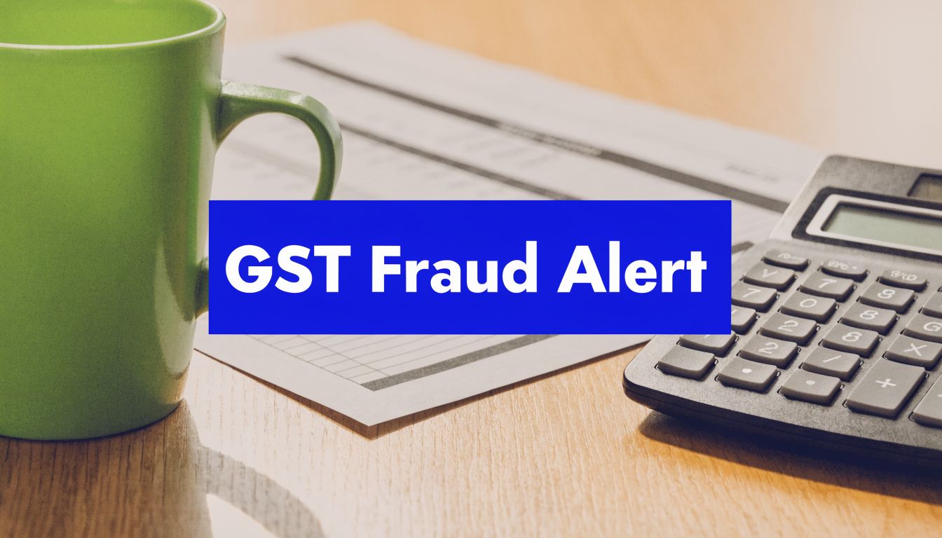 GST fraud alert banner displayed over a desk with a calculator, paperwork, and coffee mug.