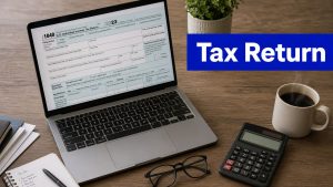 Laptop displaying a tax return form on a desk with a calculator, coffee cup, glasses, notebook, and large “Tax Return” text overlay.